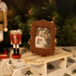Biscuit cadre brun avec photo de deux personnes, présenté sur une luge dans un décor de Noël.