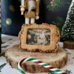 Biscuit cadre avec photo d’un enfant, posé sur un rondin devant un sapin miniature.