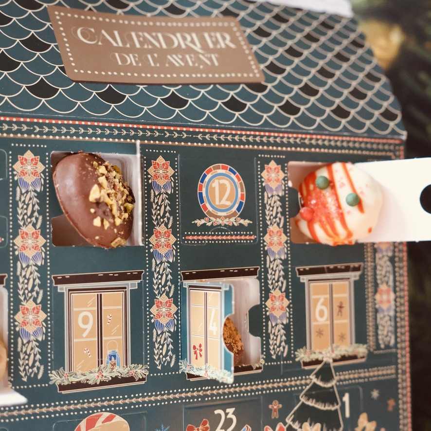Détail des cases ouvertes du calendrier de l’Avent avec des biscuits enrobés et décorés.