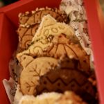 Détail de l’assortiment de biscuits boules de Noël aux motifs flocon, pois et lignes dans un coffret rouge.
