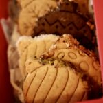 Gros plan sur les biscuits boules gravés et leurs bordures variées dans un coffret rouge.