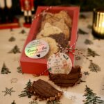 Coffret rouge de biscuits surprises avec un biscuit cassé révélant le message Un moment de gourmandise et de magie.